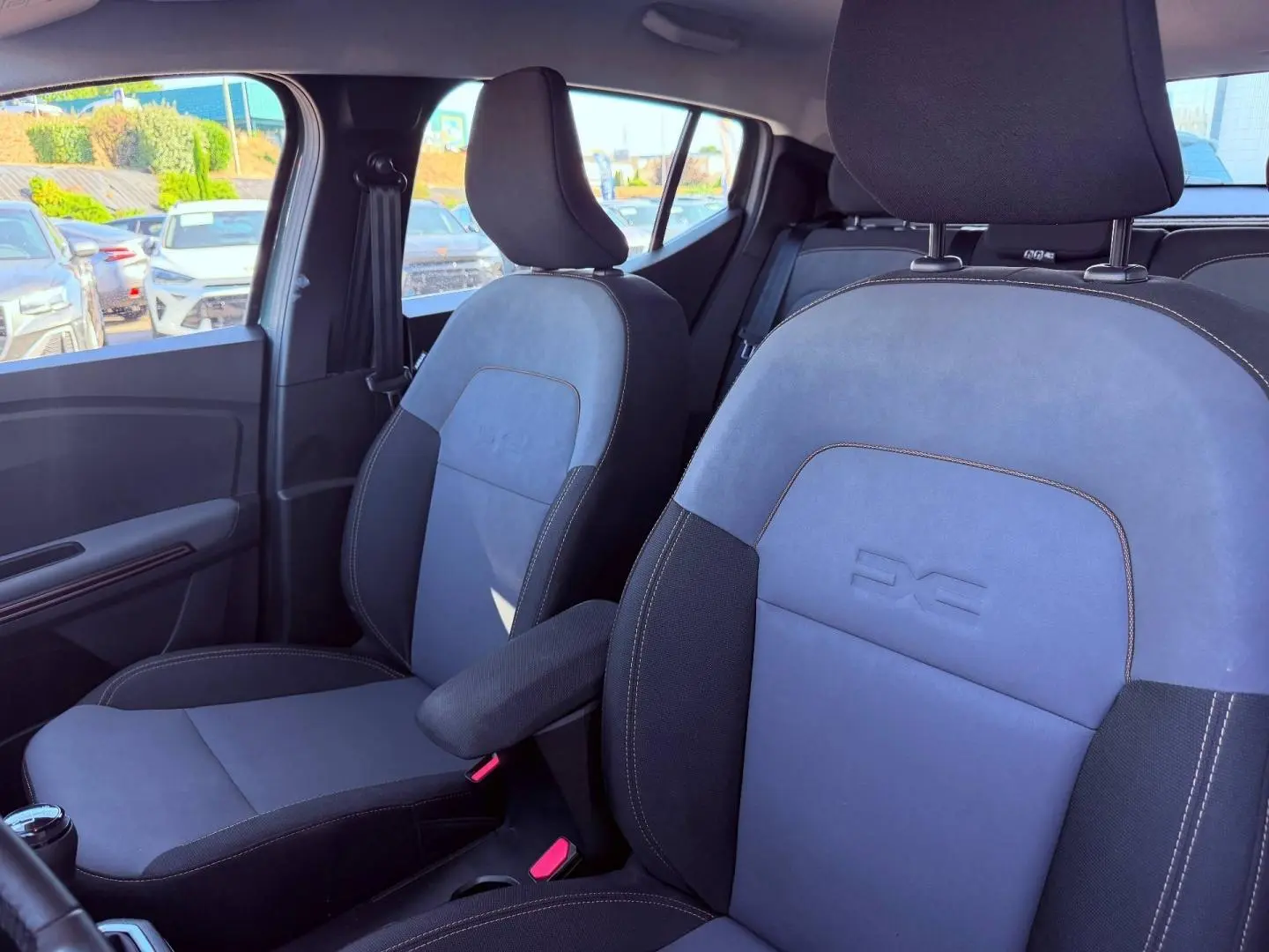 Vue intérieure des sièges avant de la Dacia Sandero Stepway Extreme avec tissu brun cuivré et accoudoir central.