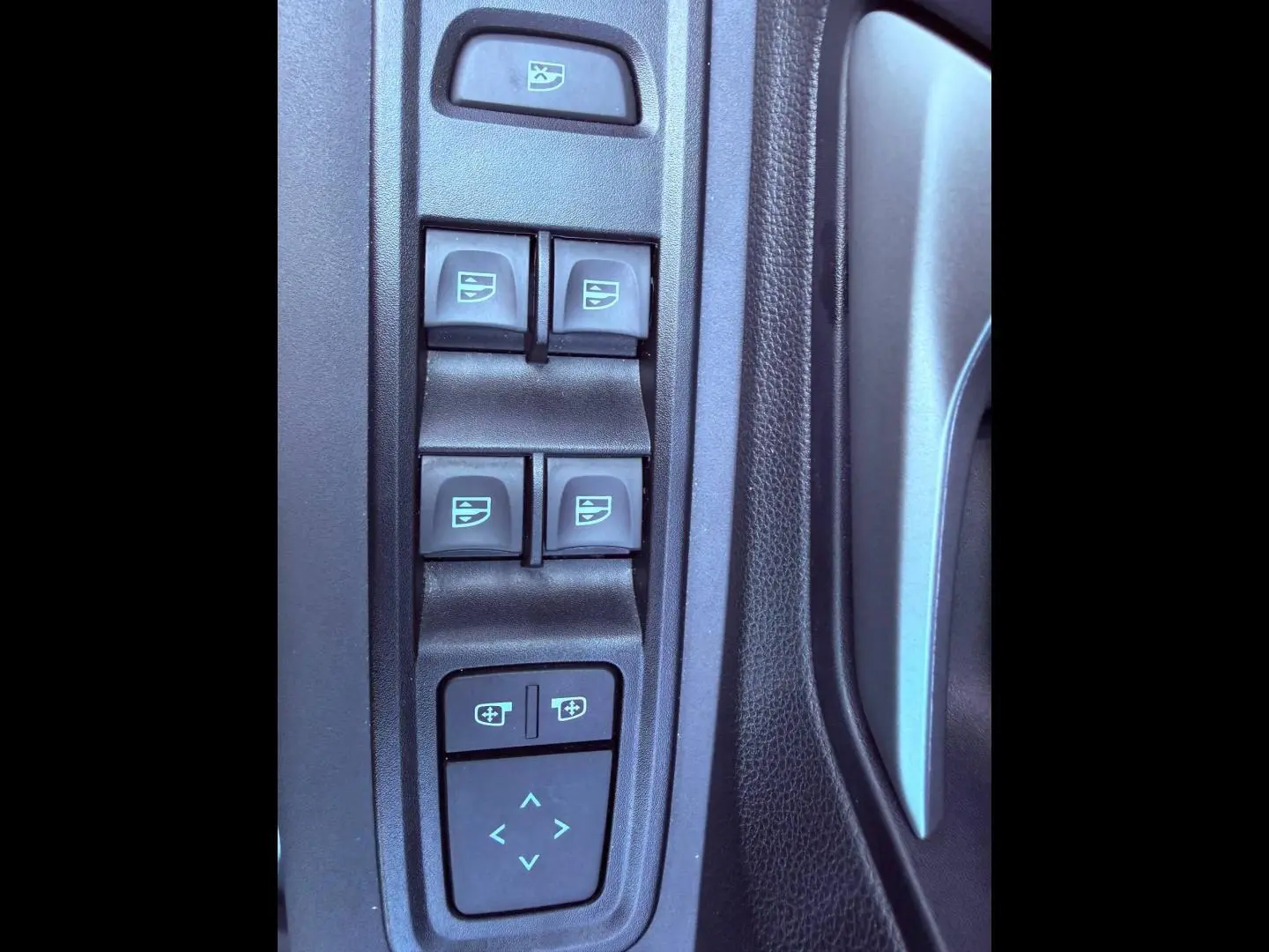 Gros plan sur les commandes des vitres électriques et réglages des rétroviseurs côté conducteur du Dacia Sandero 2025.