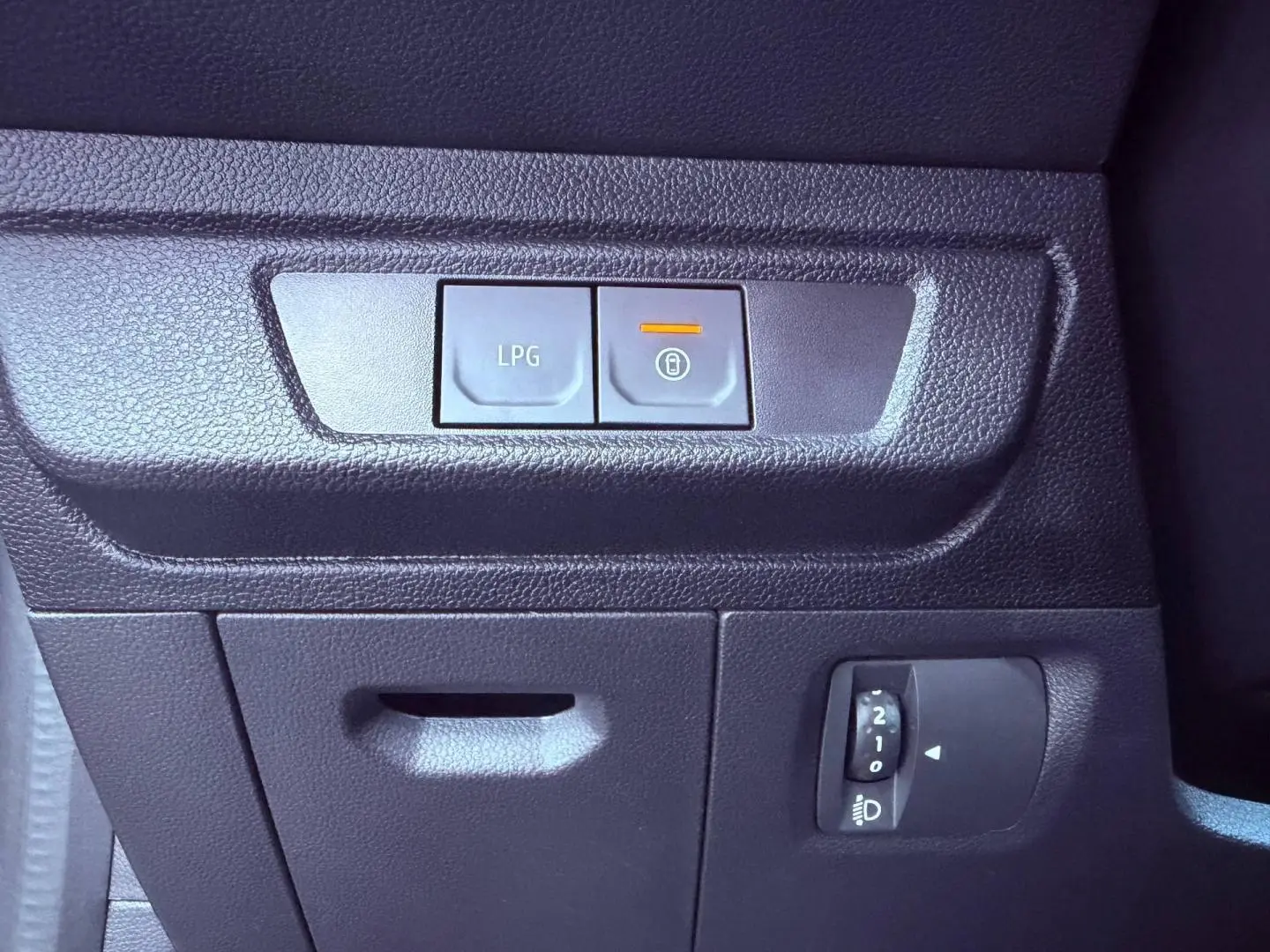 Gros plan sur les commandes intérieures noires avec bouton LPG et réglage des phares, tableau de bord Dacia Sandero 2025.