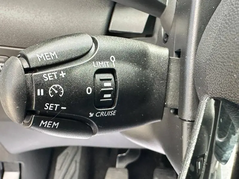 Gros plan sur la commande de régulateur de vitesse noir du Citroën C3 Aircross PureTech 110ch 2021, intérieur noir.