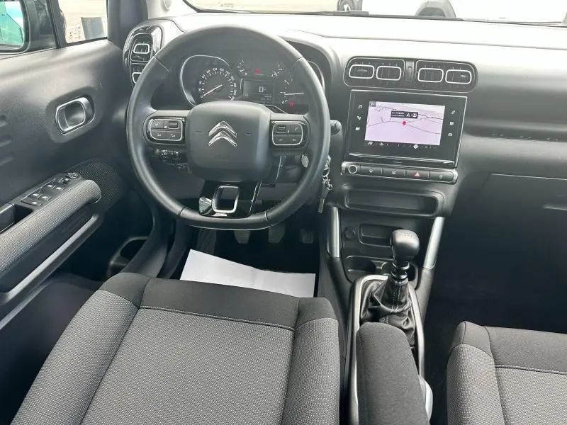Vue intérieure avant du Citroën C3 Aircross 2021, volant cuir noir, écran tactile GPS et sièges tissu gris Mica Grey.