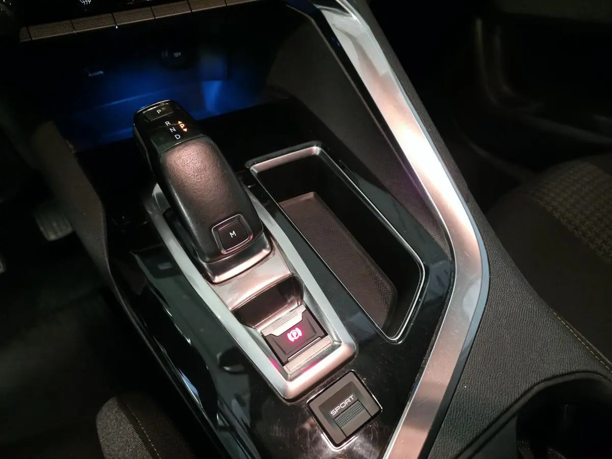 Gros plan sur la console centrale du Peugeot 5008 bleu, mettant en valeur le levier de vitesse automatique et bouton sport.
