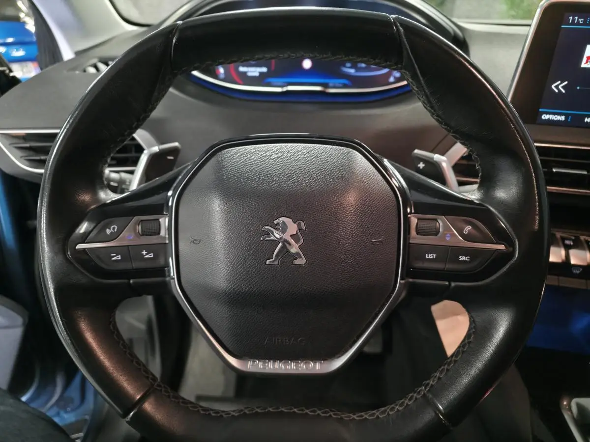 Volant cuir noir de Peugeot 5008 2019 vu de face avec commandes intégrées et tableau de bord numérique en arrière-plan.