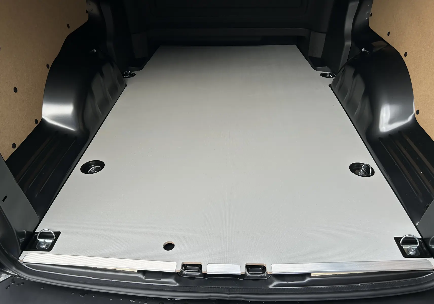 Vue arrière du coffre spacieux du Citroën Jumpy Long L3 gris titane, avec plancher plat et fixations métalliques visibles.
