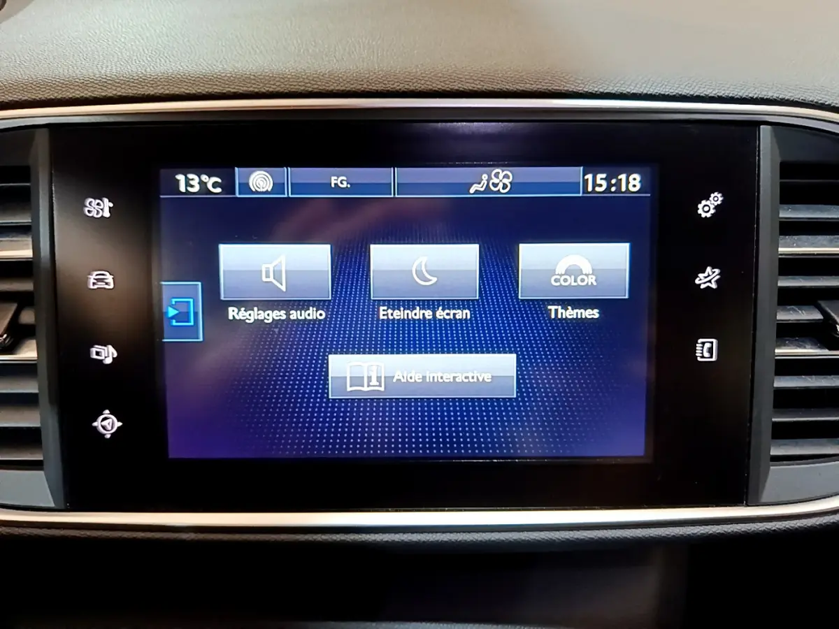 Écran tactile central de la Peugeot 308 gris foncé, affichant le menu des réglages audio et thèmes.
