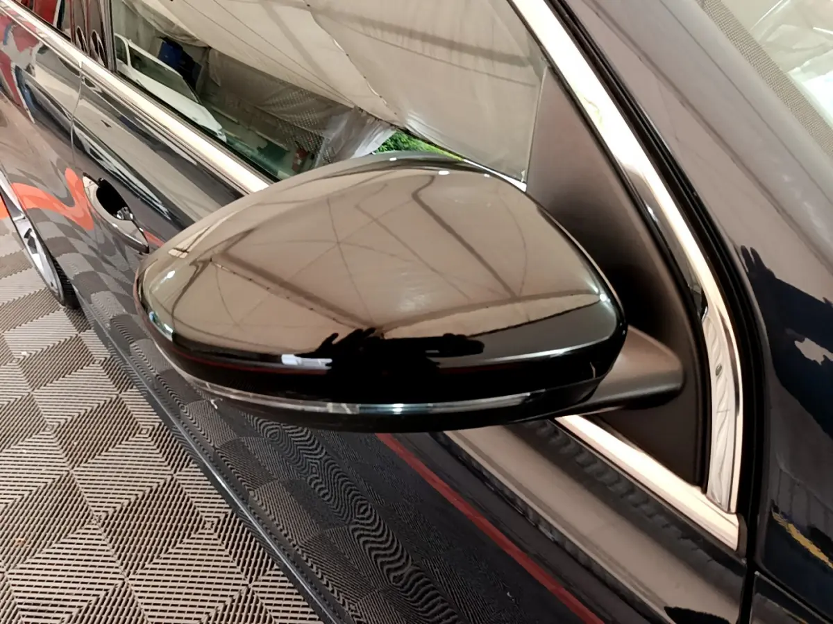 Gros plan sur le rétroviseur droit gris foncé brillant de la Peugeot 308 GT Line 2016, avec reflet de l’environnement.