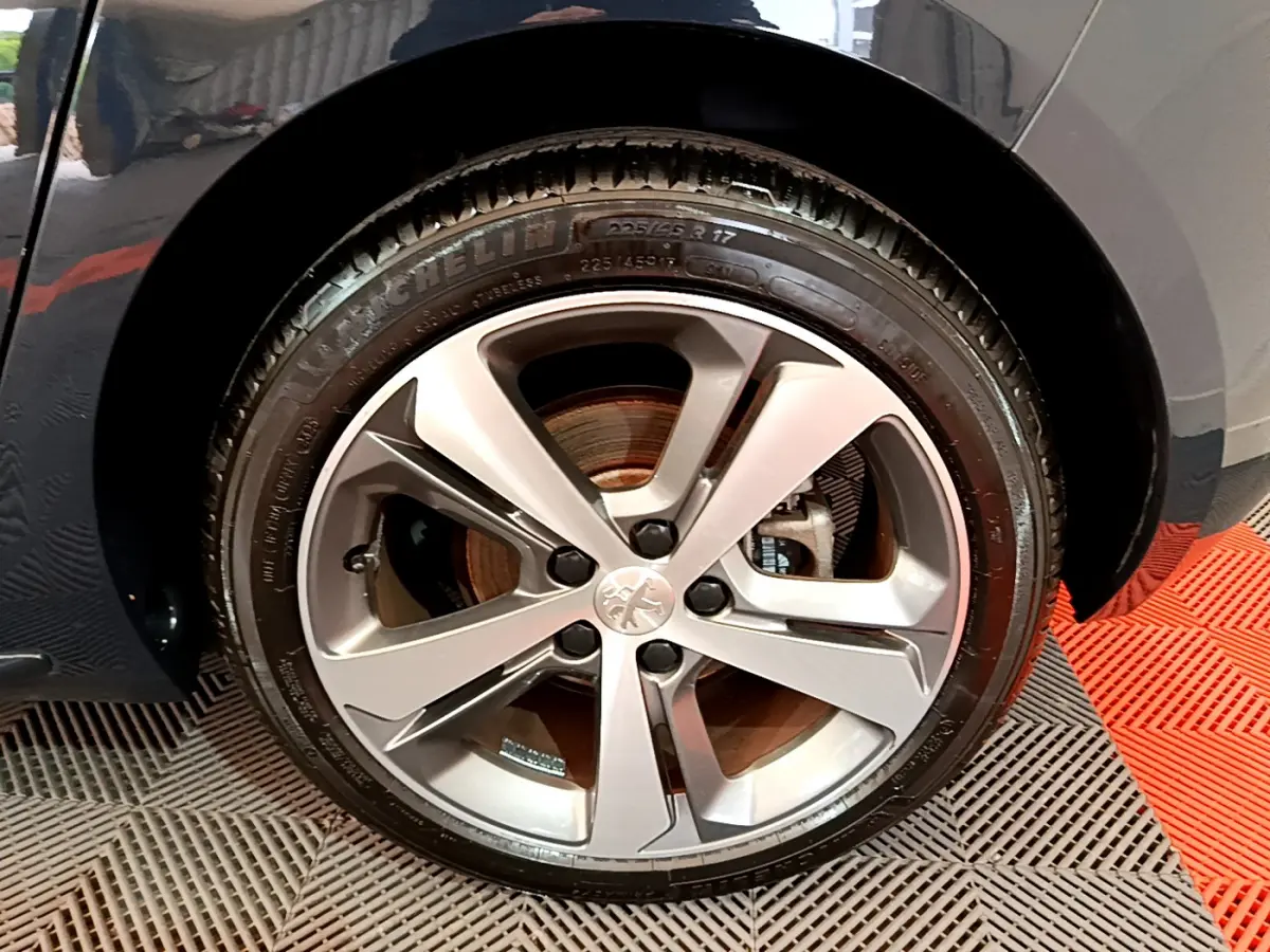 Gros plan sur la roue avant droite de la Peugeot 308 gris foncé, mettant en valeur la jante alliage et le pneu Michelin.