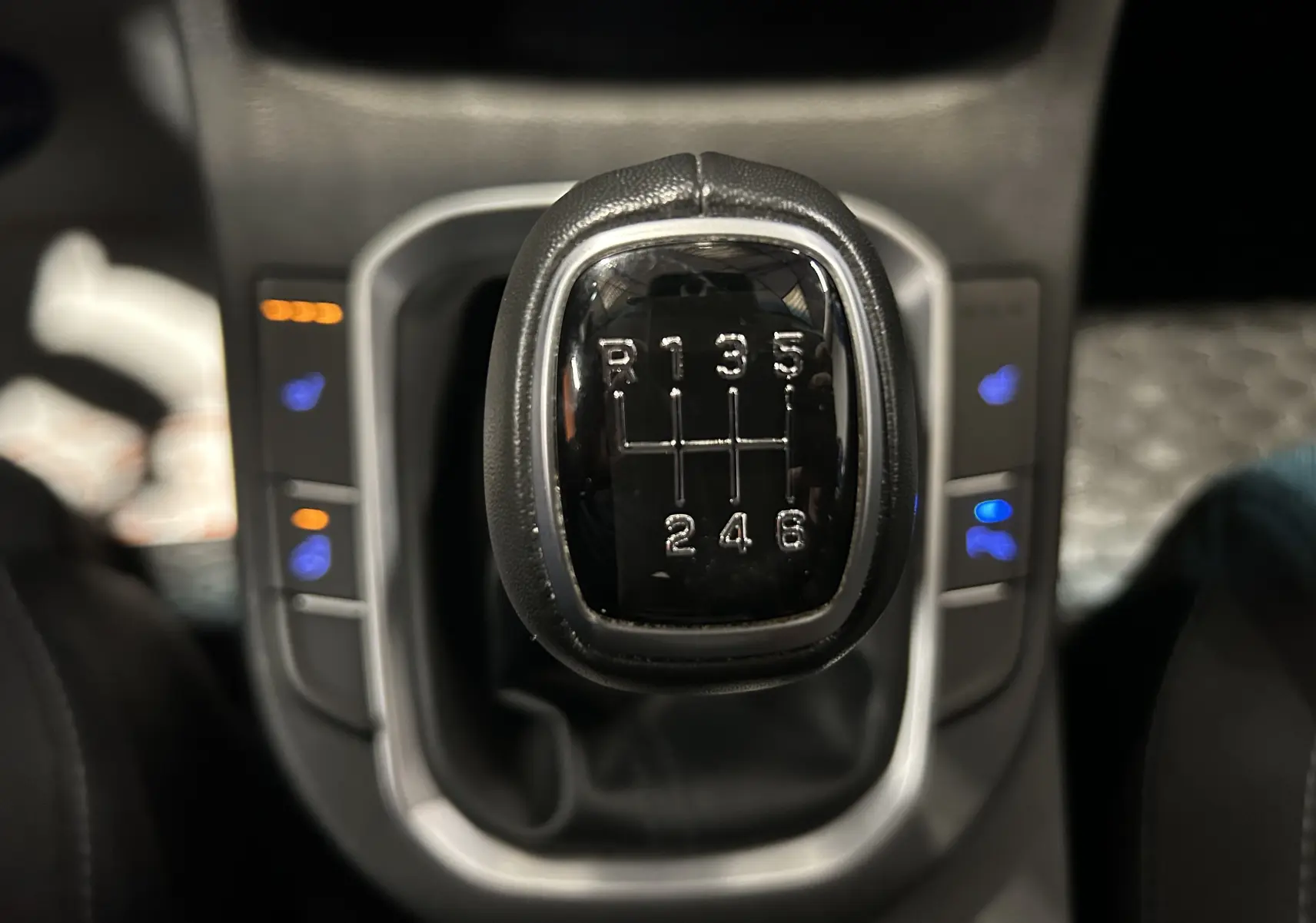 Gros plan sur le levier de vitesses manuel noir de la Hyundai i30 SW 2022 avec boutons de sièges chauffants illuminés.