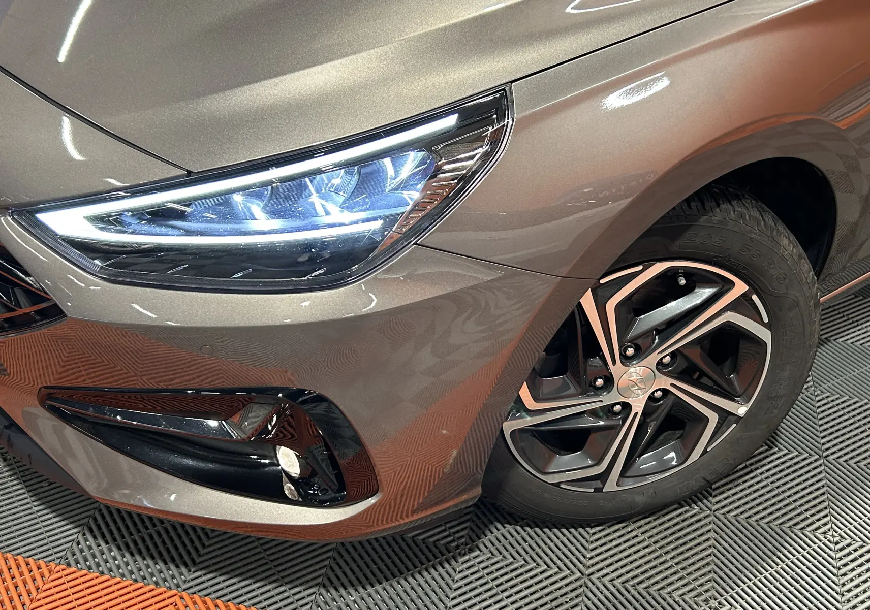 Gros plan sur le phare avant gauche et la roue en alliage de la Hyundai i30 SW 2022 couleur bronze métallique.