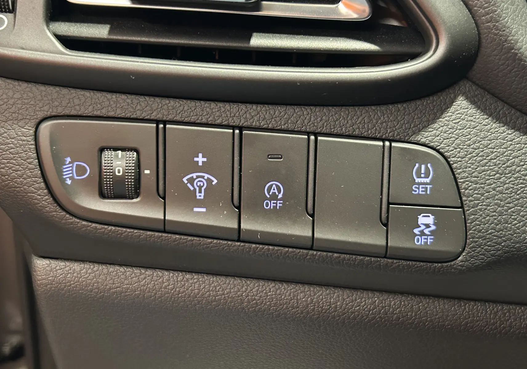 Gros plan sur les boutons de réglage d'éclairage et d'assistance du tableau de bord d'une Hyundai i30 SW 2022 couleur Silky Bronze.