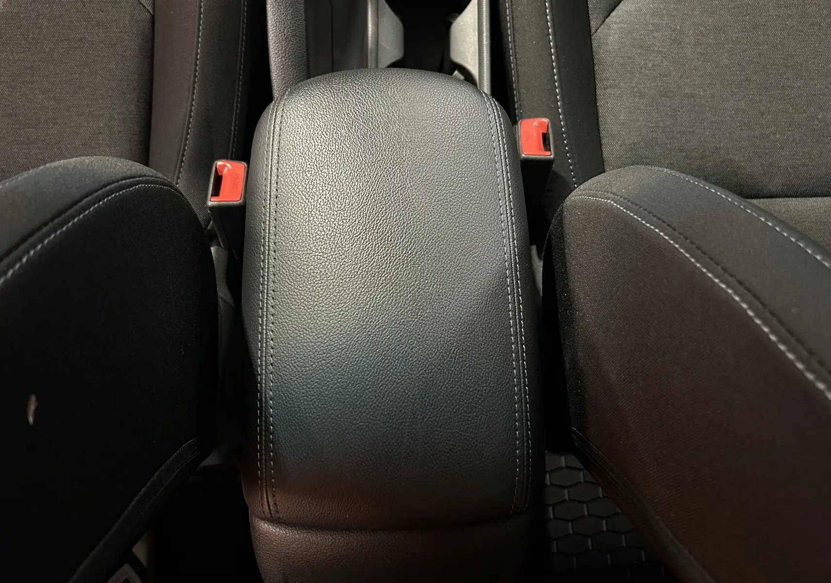 Gros plan sur l'accoudoir central en cuir noir et les sièges en tissu gris foncé de la Hyundai i30 SW 2022.