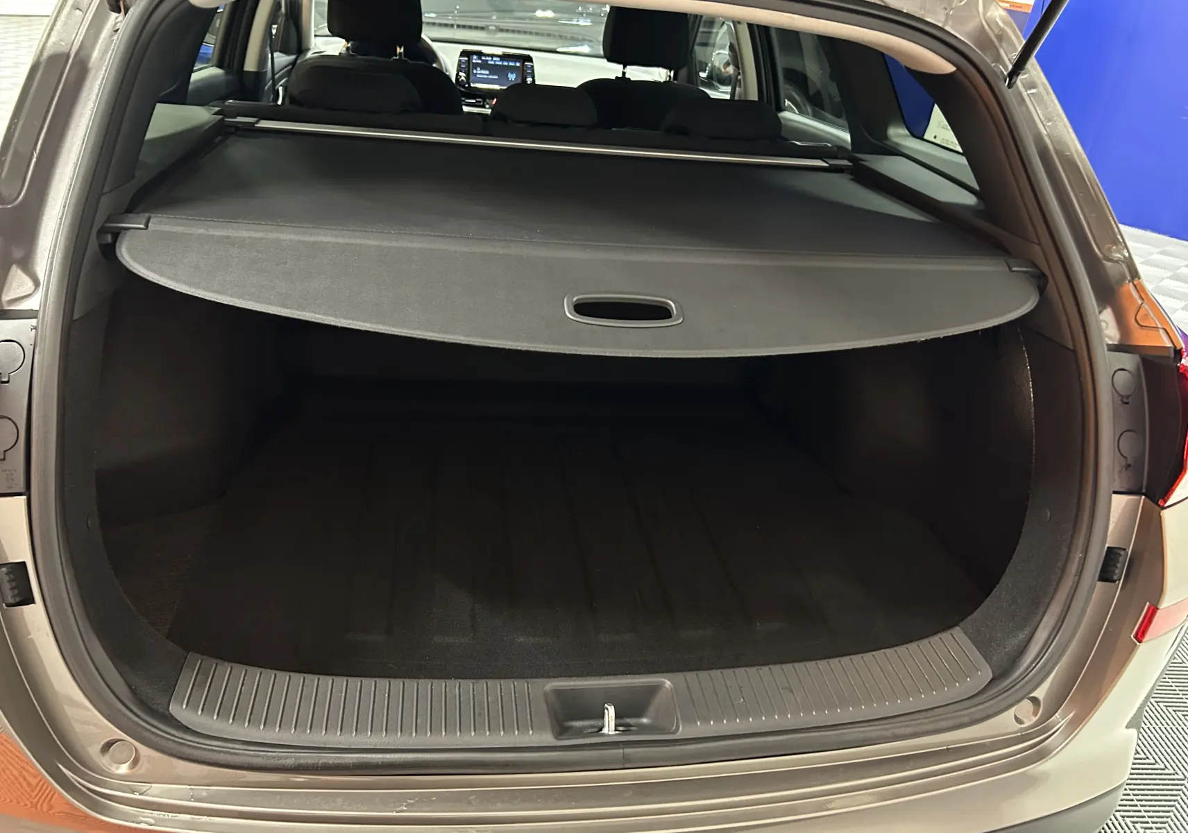 Coffre ouvert vu de l'arrière d'une Hyundai i30 SW 2022 couleur bronze métallique avec cache-bagages déployé.