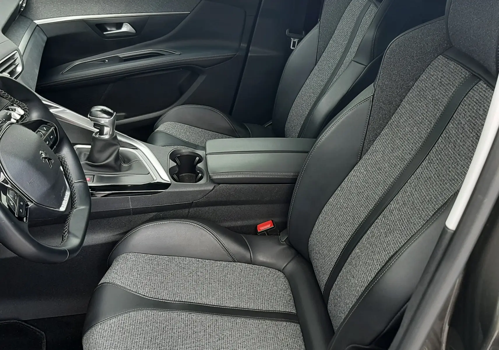 Vue intérieure côté conducteur du Peugeot 3008 2019, sièges tissu et cuir gris avec console centrale et levier de vitesse manuel.