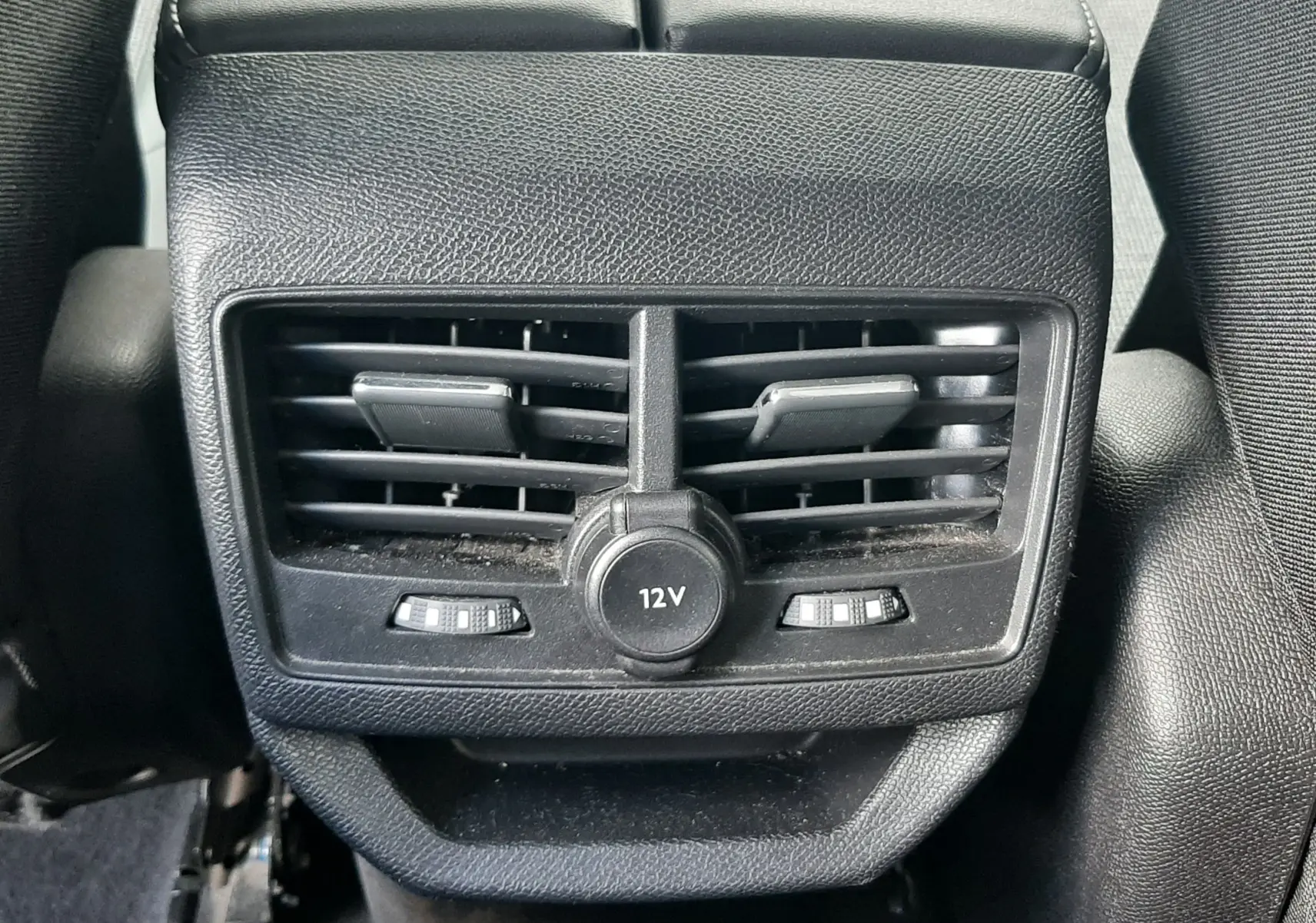 Vue rapprochée des aérateurs arrière noirs et prise 12V au centre du Peugeot 3008 gris Amazonite de 2019.