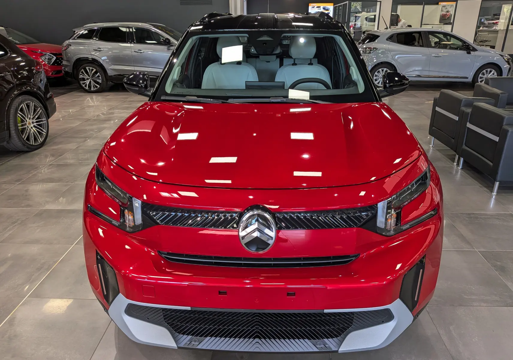 Vue avant d’un Citroën C3 Aircross 2026 rouge Elixir avec toit noir, en showroom, soulignant sa calandre moderne et ses phares LED.