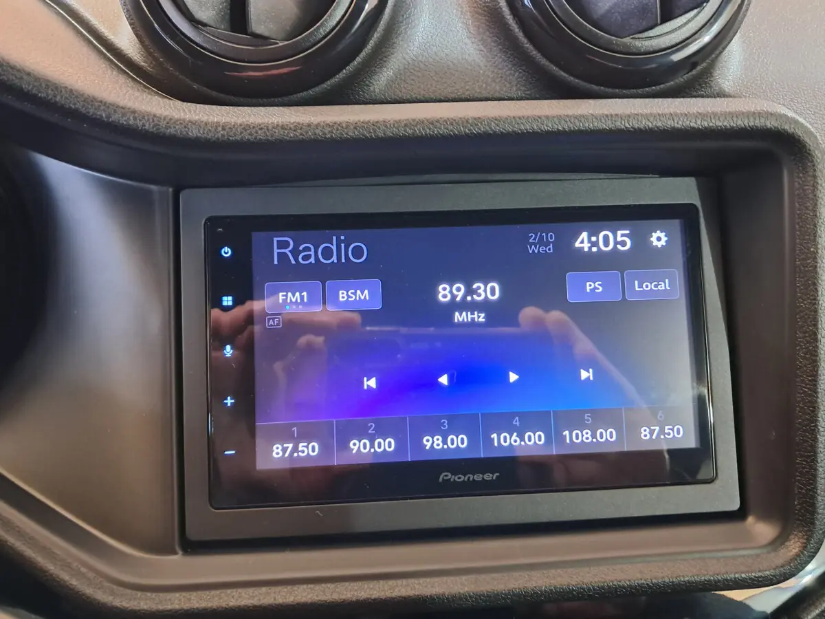 Écran tactile Pioneer de la radio FM affichant 89,30 MHz dans l'habitacle d'une Aixam Ambition rouge 2025.