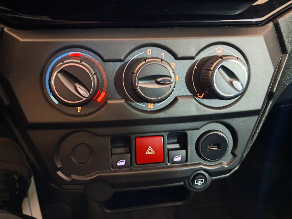 Tableau de bord de l'AIXAM AMBITION 2025 montrant les commandes de climatisation et les boutons de sécurité en gros plan.