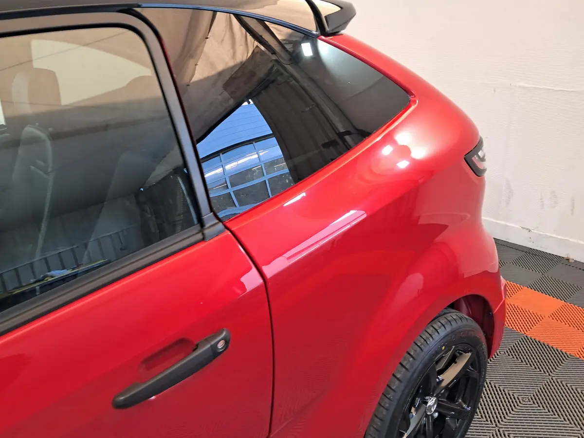 Vue rapprochée du côté gauche arrière d'une AIXAM AMBITION rouge 2025 avec jante noire brillante.