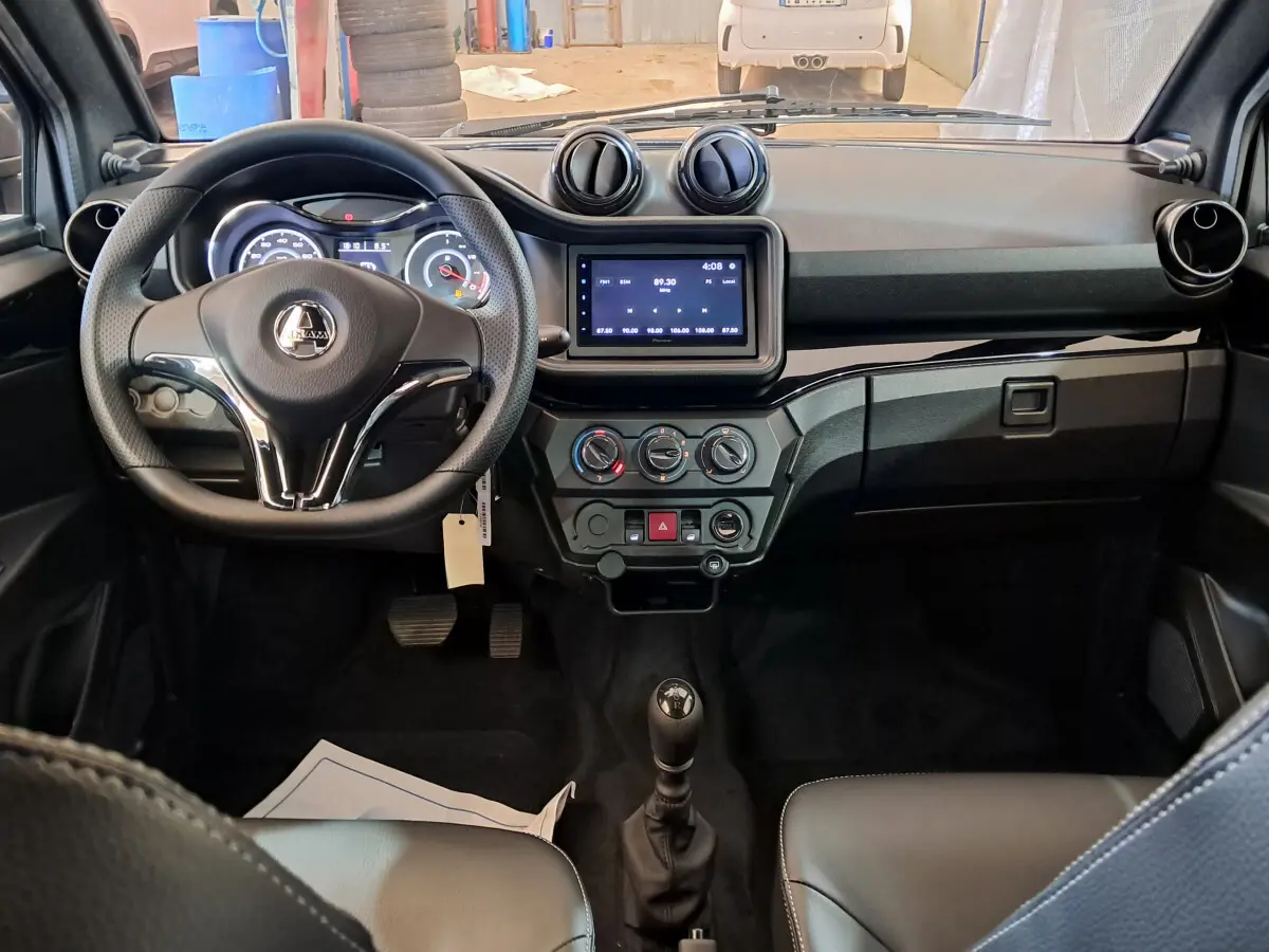 Vue intérieure frontale de l'AIXAM AMBITION rouge 2025, tableau de bord avec écran tactile et volant multifonction.