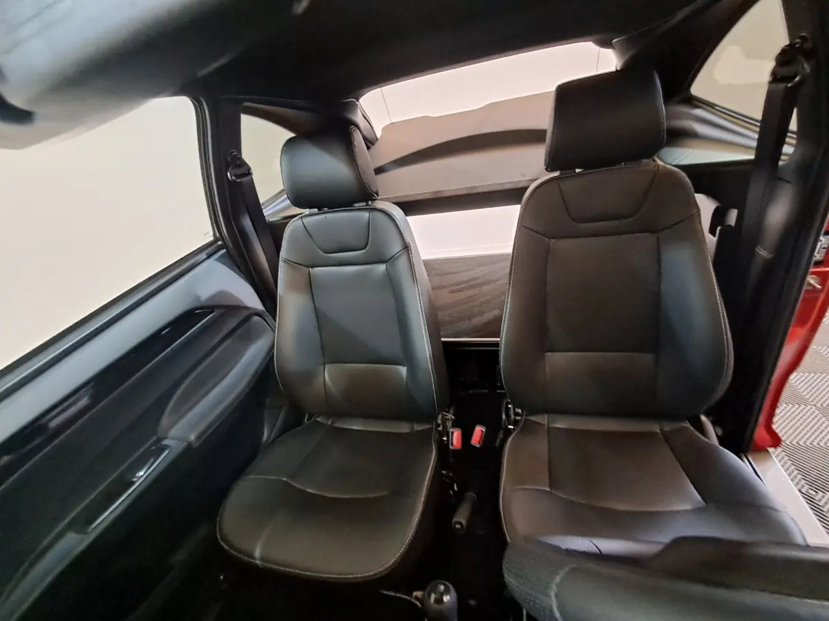 Vue intérieure frontale des sièges avant en cuir noir de l'AIXAM AMBITION 2025 rouge, version City Coupe Sport.