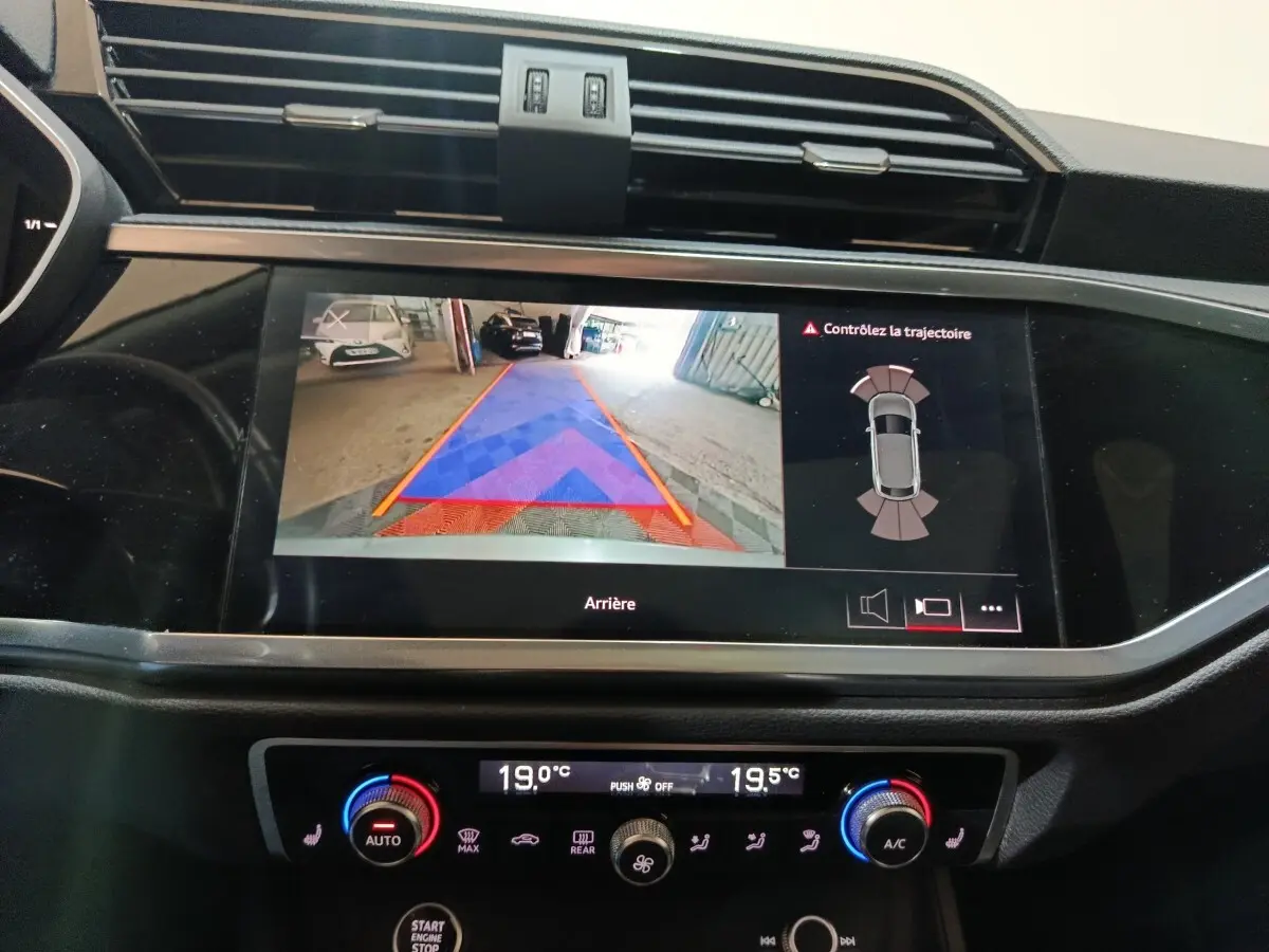 Écran tactile intérieur de l'Audi Q3 Sportback 45 TFSI e 2021 montrant l'aide au stationnement arrière avec guidage couleur.