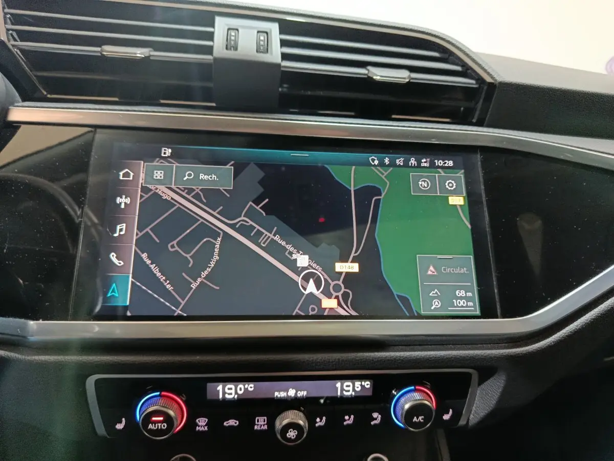 Vue rapprochée de l’écran tactile central et de la commande de climatisation du tableau de bord de l’Audi Q3 Sportback gris foncé.