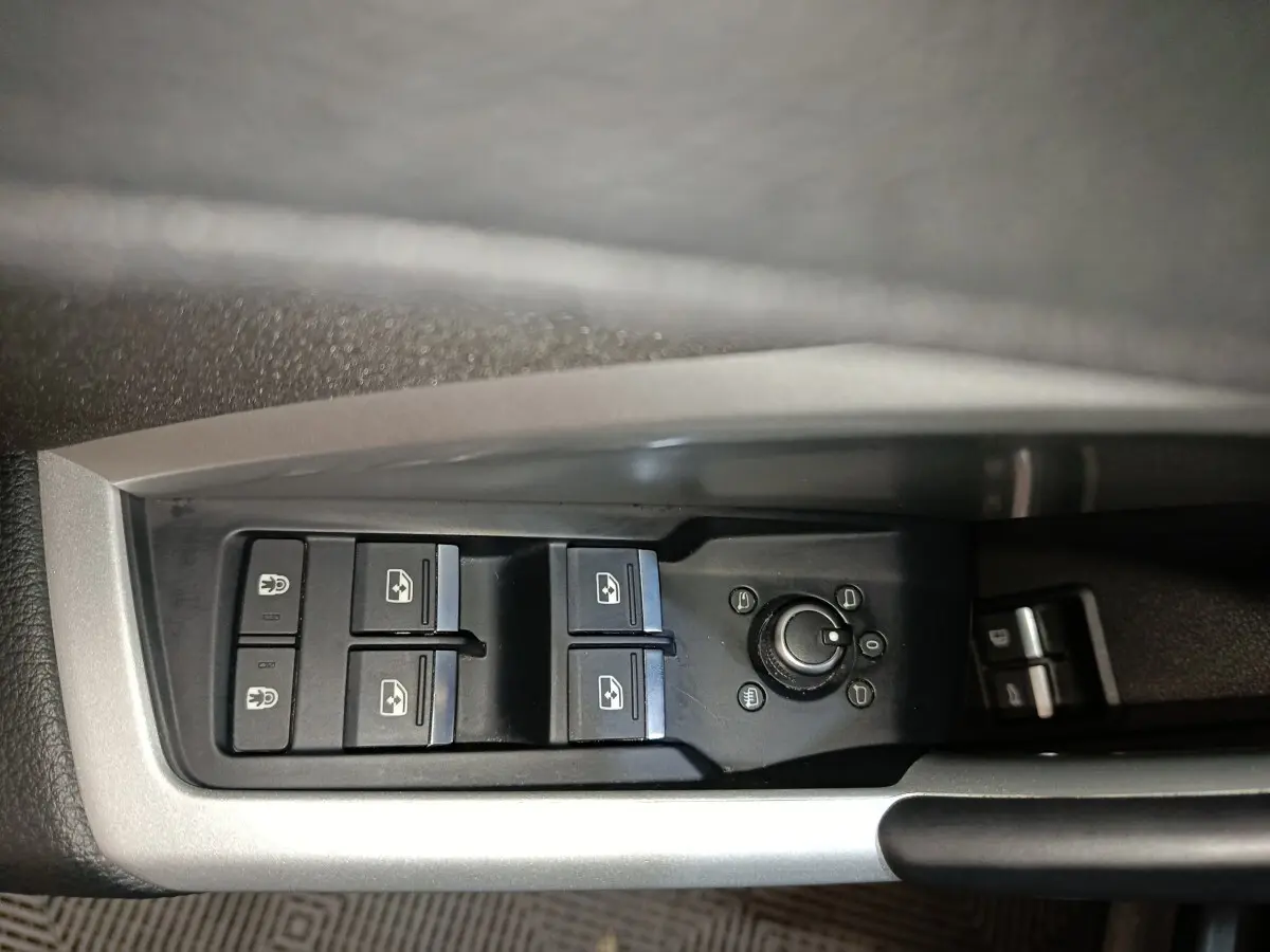 Gros plan sur les commandes des vitres électriques et rétroviseurs côté gauche de l'Audi Q3 Sportback gris foncé.