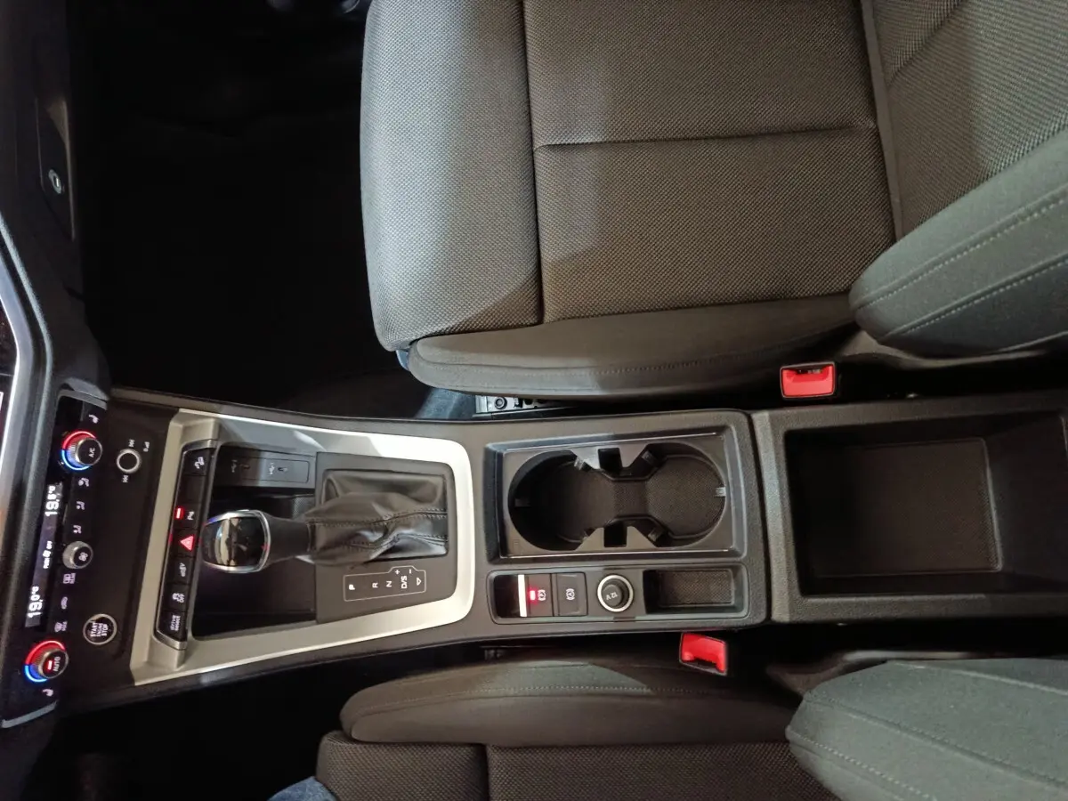 Vue plongeante sur la console centrale noire de l'Audi Q3 Sportback 45 TFSI E avec levier de vitesse et porte-gobelets.