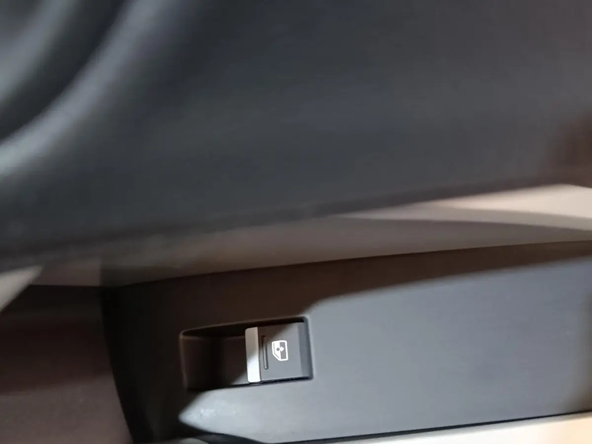 Gros plan sur le bouton de commande de la vitre électrique côté conducteur dans l’habitacle d’un Audi Q3 Sportback gris foncé.