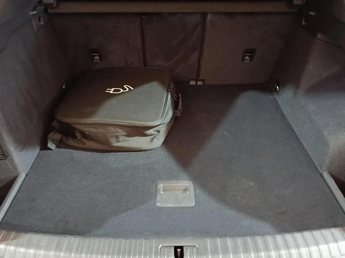 Coffre ouvert vu de face de l’Audi Q3 Sportback gris foncé avec sac de charge hybride posé à gauche.
