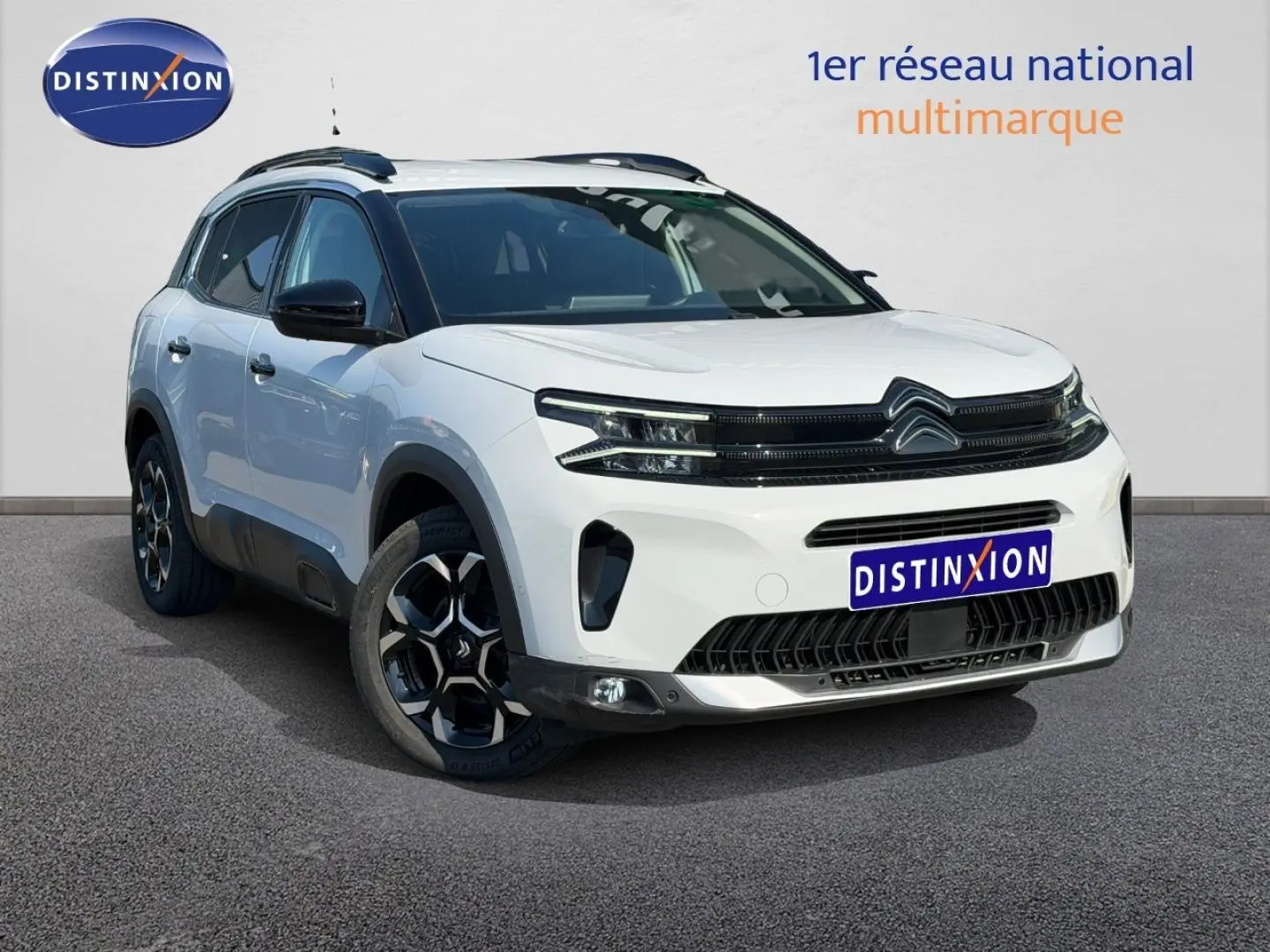Vue 3/4 avant droite du Citroën C5 Aircross blanc Okénite avec jantes alu et barres de toit noires.