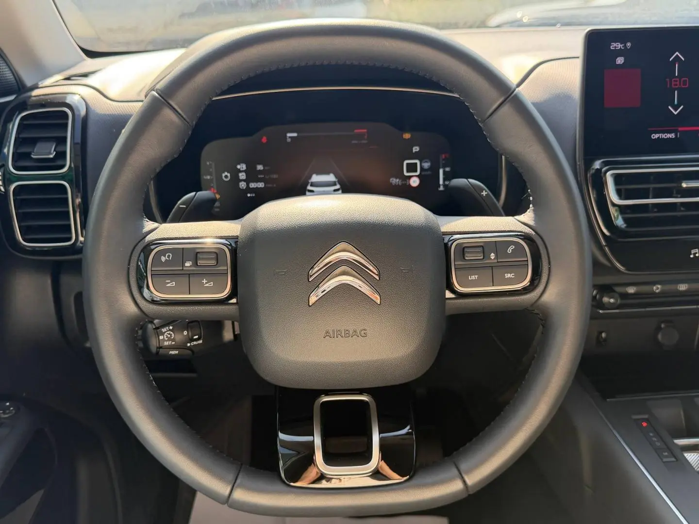 Vue rapprochée du volant cuir multifonction noir du Citroën C5 Aircross avec tableau de bord digital en arrière-plan.