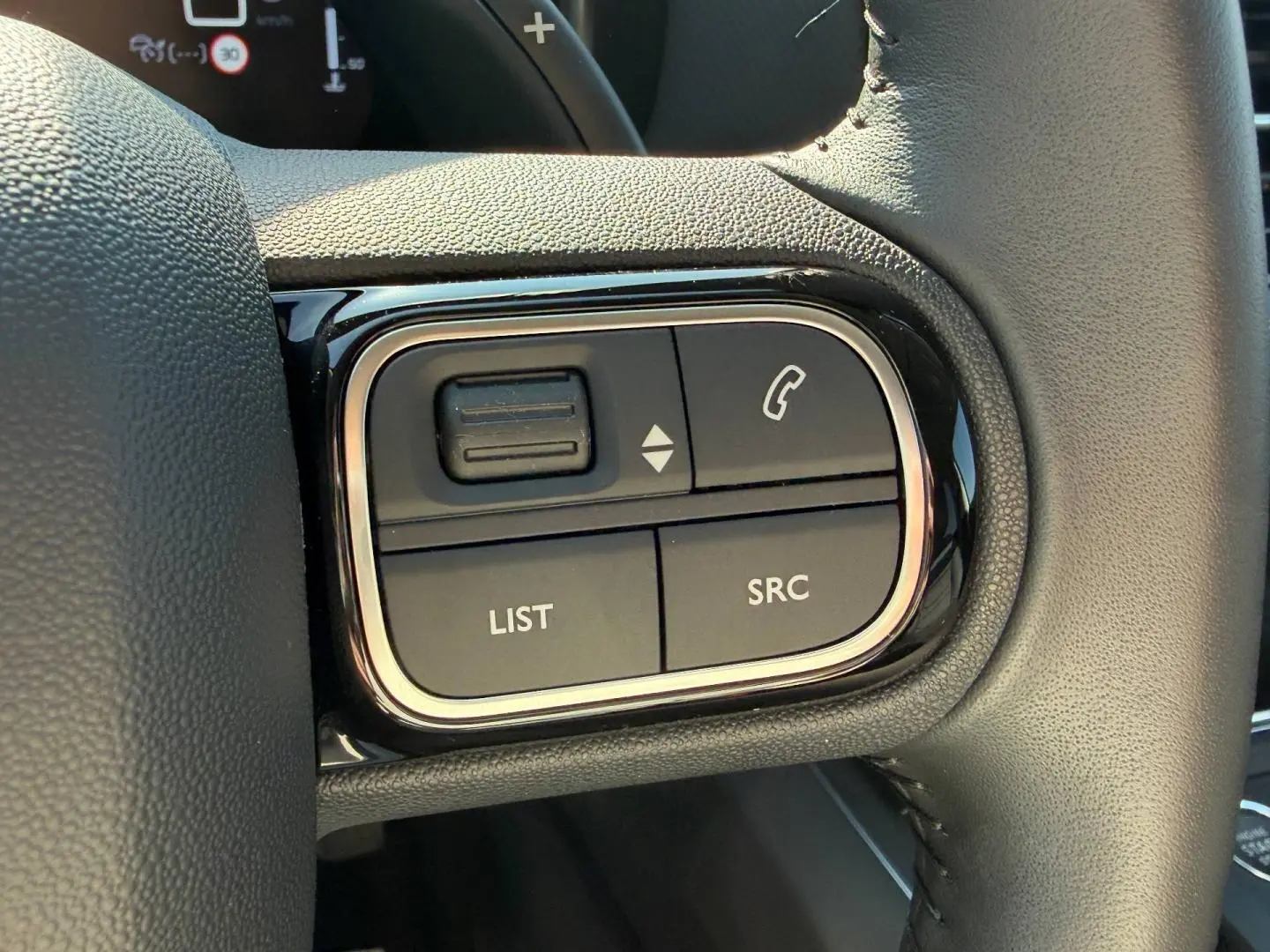 Gros plan sur les commandes multifonctions gauche du volant cuir du Citroën C5 Aircross blanc Okénite 2025.