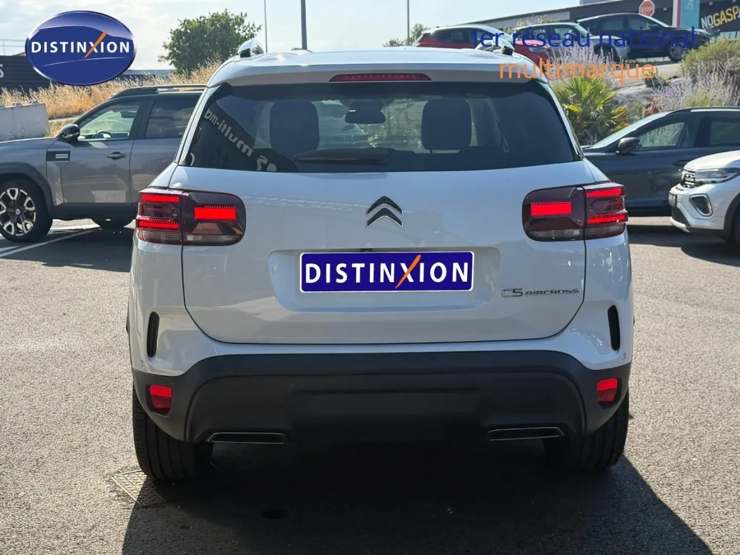 Vue arrière d'un Citroën C5 Aircross blanc Okénite avec feux LED et barres de toit visibles en extérieur.