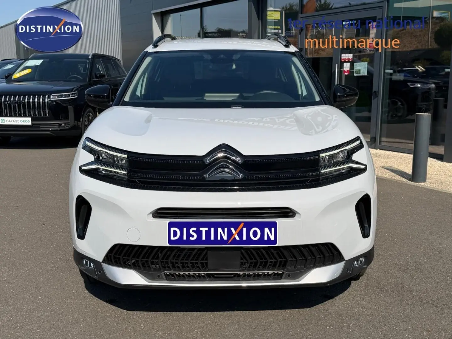 Vue de face du Citroën C5 Aircross blanc Okénite avec calandre noire et barres de toit visibles.