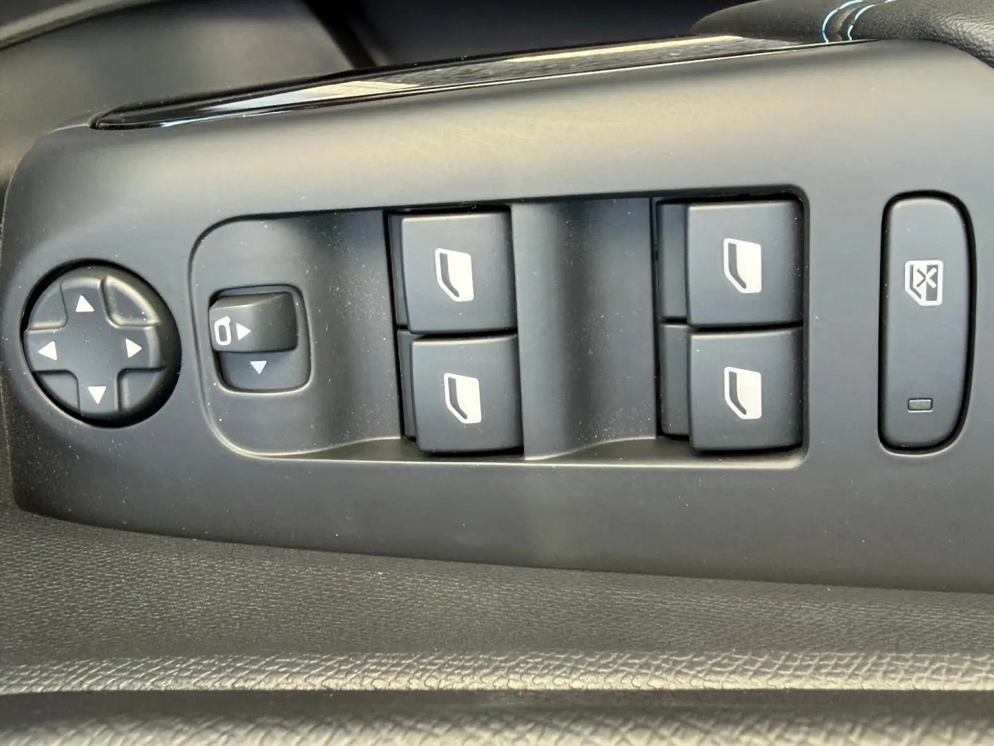 Vue rapprochée des commandes de lève-vitres et rétroviseurs sur la porte côté gauche du Citroën C5 Aircross blanc Okénite.