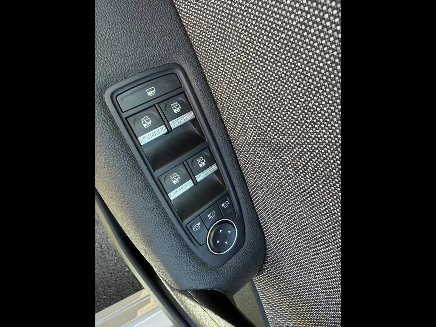 Gros plan sur les commandes des vitres électriques et rétroviseurs sur la porte avant gauche du Renault Captur gris Rafale.