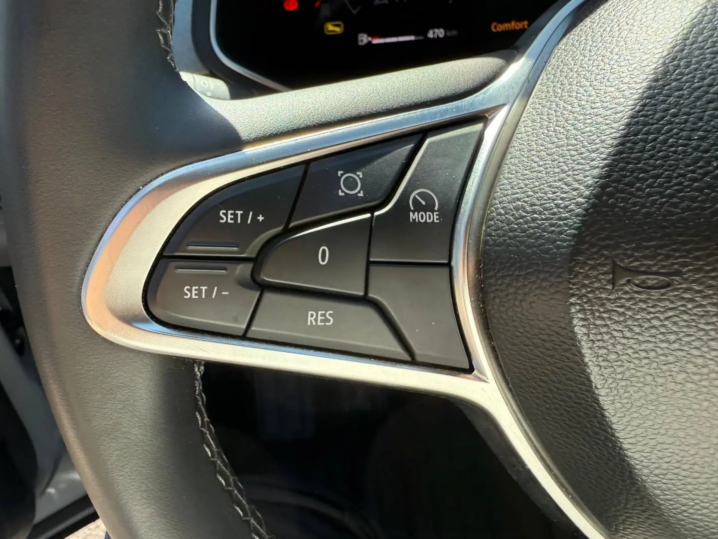 Gros plan sur les commandes de régulateur de vitesse à gauche du volant noir du Renault Captur gris Rafale 2025.