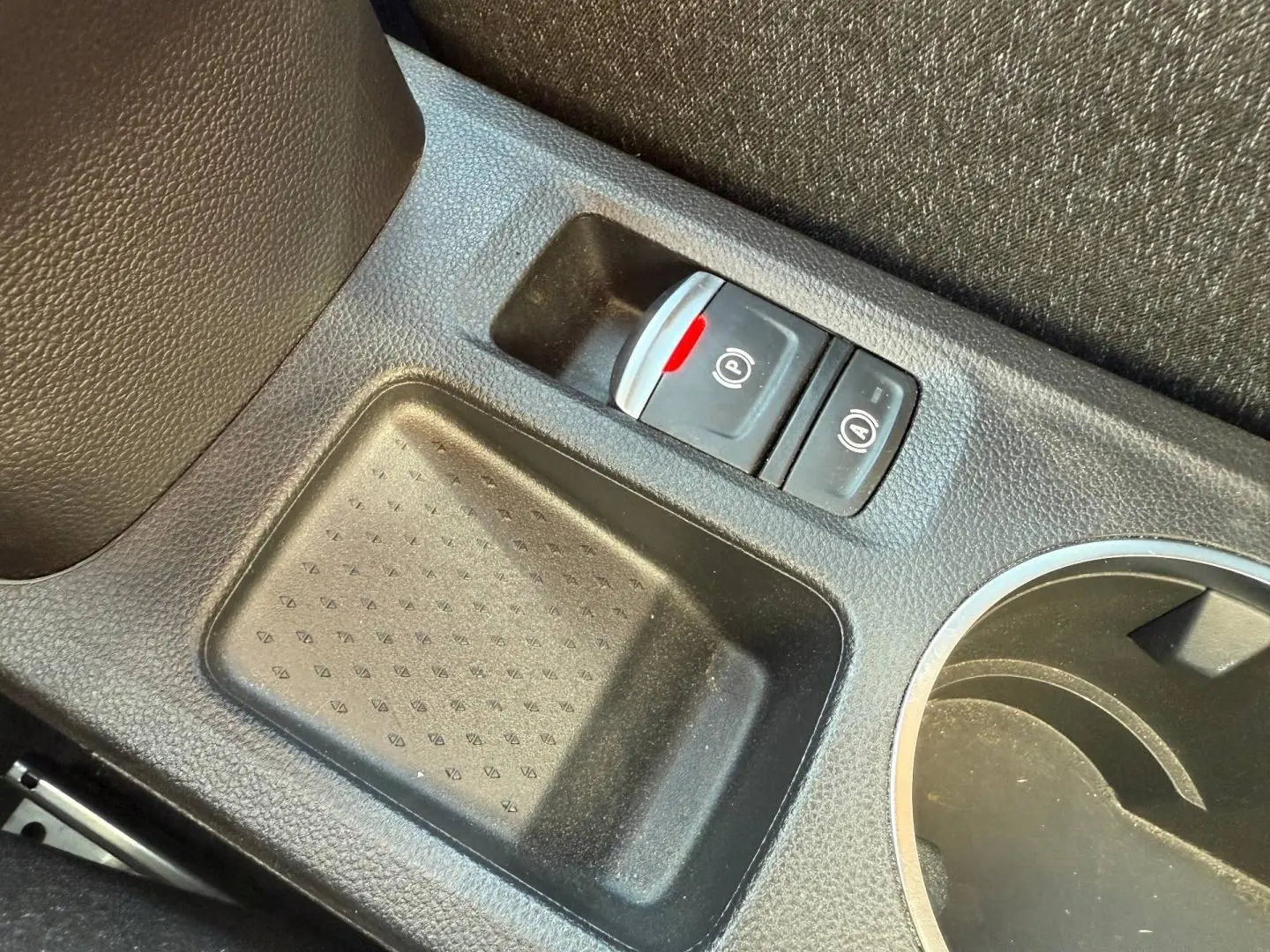 Gros plan sur la console centrale du Renault Captur 2025, montrant le frein à main électrique et porte-gobelets noirs.