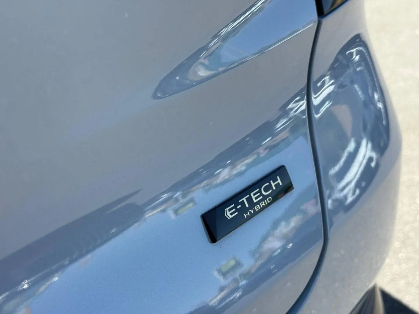 Gros plan sur l’écusson E-TECH Hybrid gris métallisé du côté gauche arrière du Renault Captur 2025.