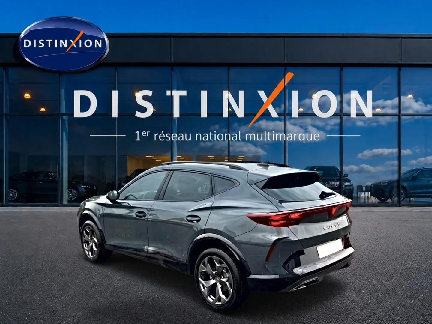 Vue 3/4 arrière droite d'un CUPRA Formentor gris métallisé stationné devant une vitrine Distinxion.