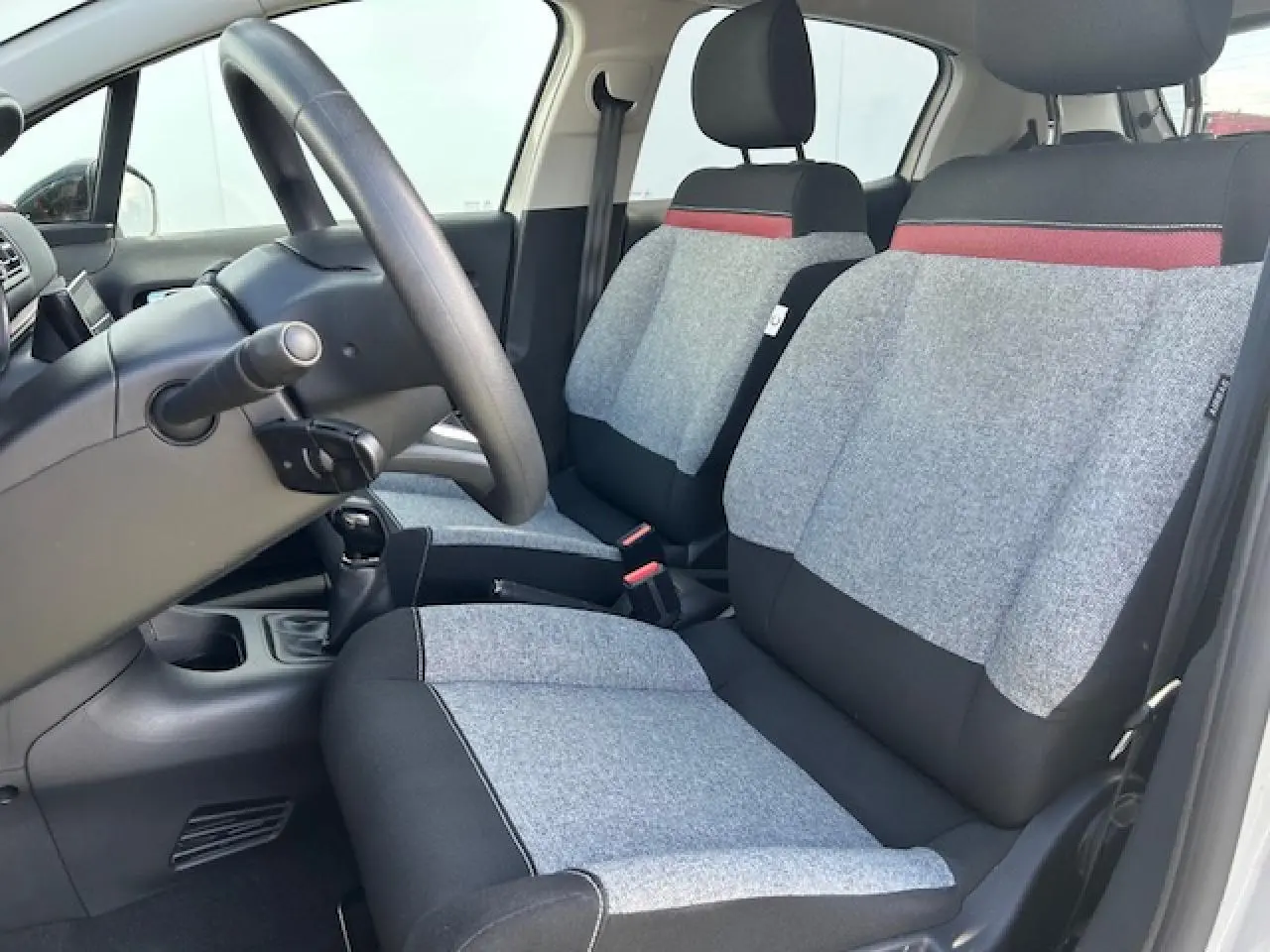 Vue intérieure côté conducteur de la Citroën C3 2021, sièges tissu gris clair avec bande rouge et noir.