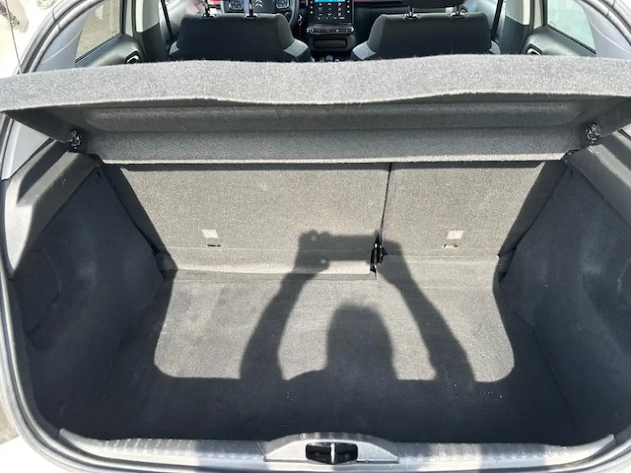 Coffre ouvert vu de l'arrière d'une Citroën C3 sable métal 2021, intérieur gris avec banquette rabattable.