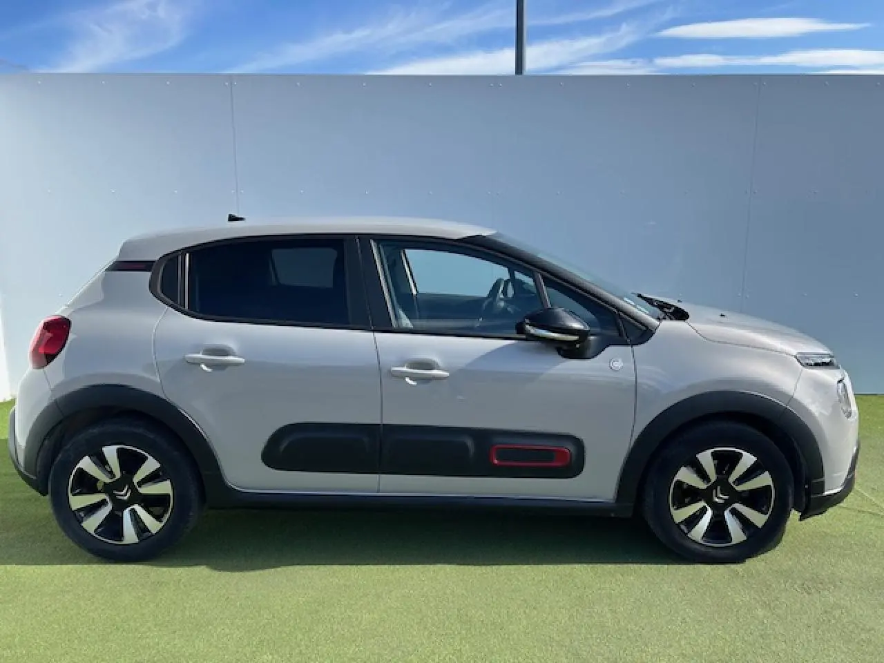 Profil côté droit d'une Citroën C3 1.2 PureTech 83 S&S C-Series sable métal avec protections latérales noires et accents rouges.