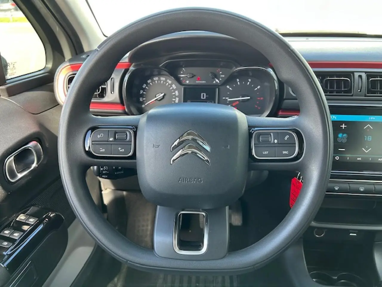 Vue centrée sur le volant noir de la Citroën C3 1.2 PureTech 83 avec tableau de bord et écran tactile rouge sable.