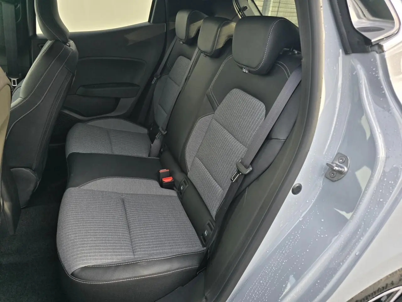 Vue intérieure côté droit sur la banquette arrière gris mélangé d'une Renault Clio V Gris Rafale Métal avec porte ouverte.