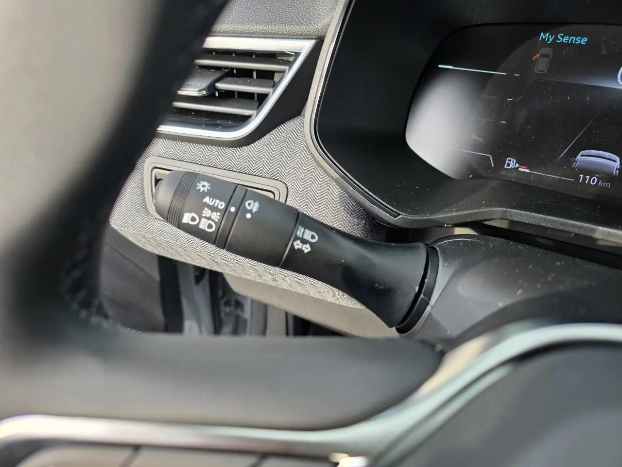 Détail du commodo d’éclairage et tableau de bord numérique avec affichage du mode My Sense dans une Renault Clio gris Rafale.