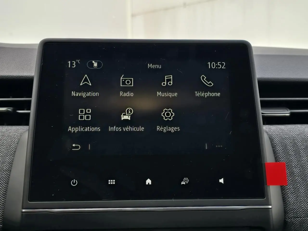Écran tactile central de la Renault Clio V 2025 affichant le menu principal avec navigation et radio, intérieur gris.