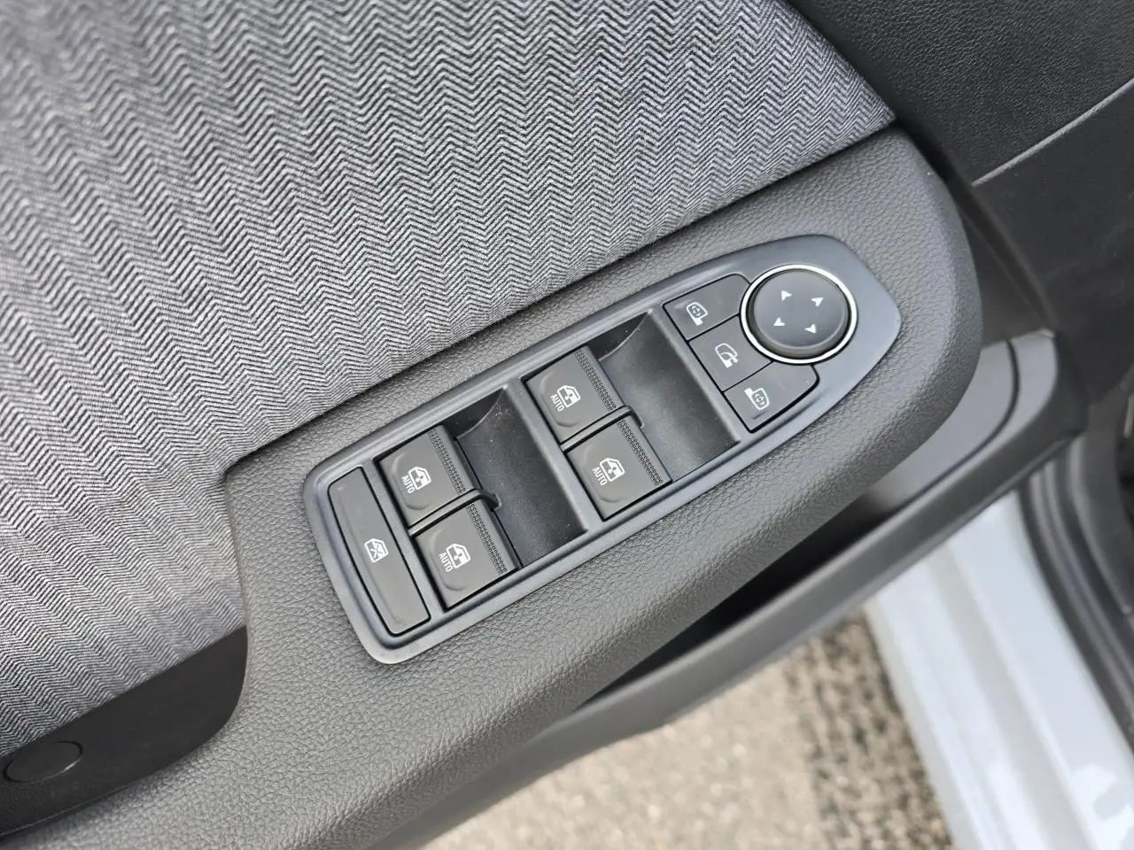 Gros plan sur les commandes des vitres et rétroviseurs côté gauche d'une Renault Clio gris Rafale métal.