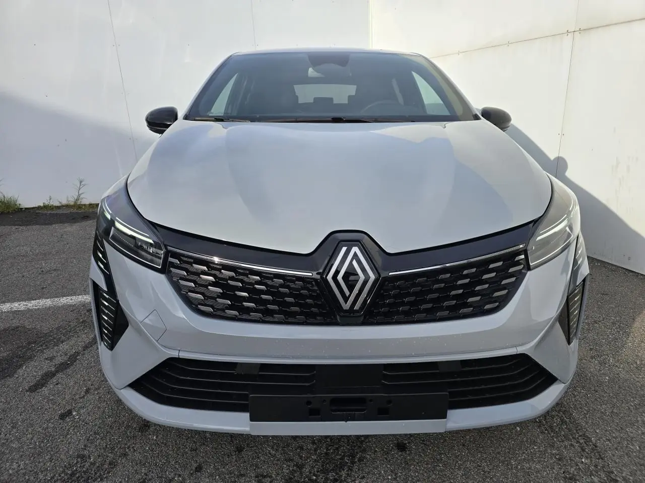Vue frontale d'une Renault Clio 2025 gris rafale métal avec calandre noire et signature lumineuse LED en C.